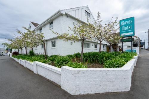 a white building with a street sign and trees at Waves Motel and Apartments in Warrnambool