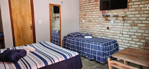 een kamer met 2 bedden, een tafel en een spiegel bij Chalé Viçosinha de Açúcar in Viçosa do Ceará