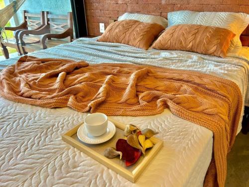 a tray with a cup and a plate of fruit on a bed at Casa La Vigie in Águas de Lindoia