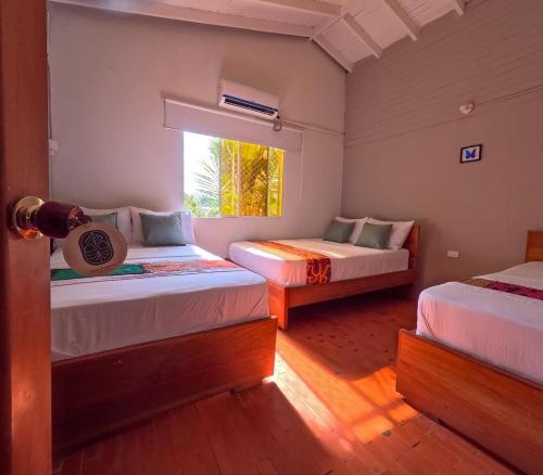 Casa Manglares Capurganá في Acanti: سريرين في غرفة بها نافذة