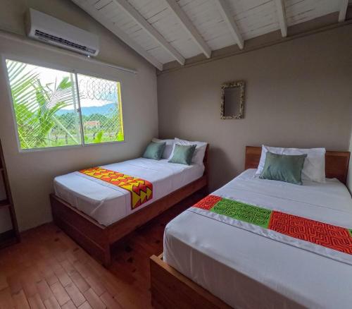 Casa Manglares Capurganá في Acanti: سريرين في غرفة بها نافذة