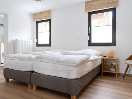 Holiday home Ahorn ground floor في Weilerswist: سرير كبير في غرفة بها نافذتين