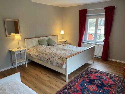 Gable house Ruppin Lake في Karwe: غرفة نوم بسرير ونافذة ذات ستائر حمراء