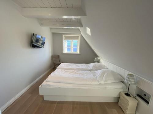 ein weißes Bett in einem Zimmer mit einer Treppe in der Unterkunft Holiday home property 46 in Utersum