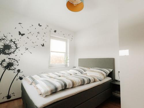 a bedroom with a bed with dandelions and butterflies on the wall at Alb holiday home Zinnäcker in Trochtelfingen