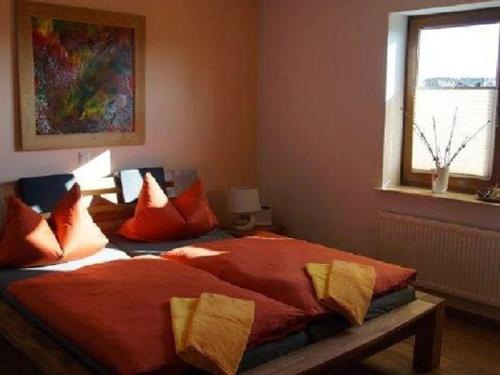 a bedroom with a bed with red sheets and a window at Holiday apartment with 3 bedrooms in Holzendorf