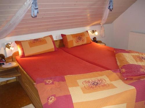 a bedroom with two beds with red sheets and a window at Close-up view inside the Vorbek house in Bärenbach