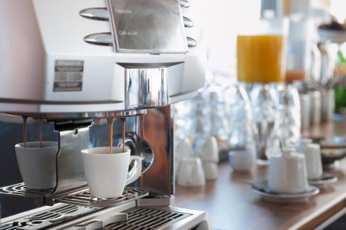 a coffee machine is making cups of coffee on a counter at Hotel de Boegschroef in Delfzijl