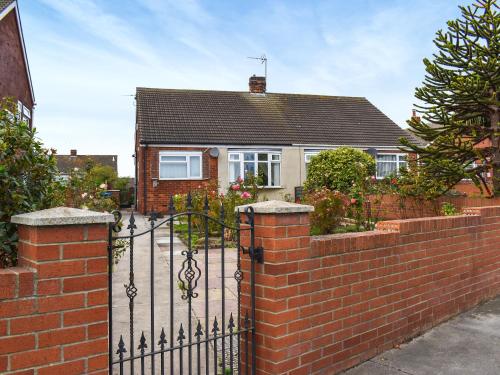 a brick fence with a gate in front of a house at Roselynne in Redcar