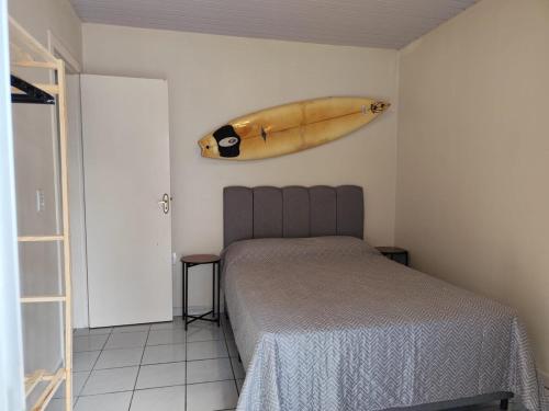 a bedroom with a bed and a surfboard on the wall at Casa Completa litoral SC com 4 qtos com ar condicionado e Aceita Pets in Itapema