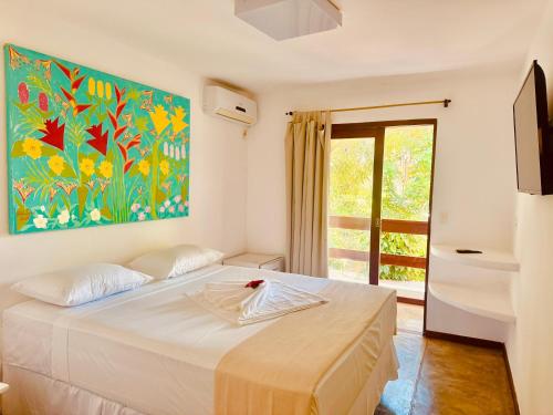 Un dormitorio con una cama con un cuadro en la pared. en Pousada Casa Palo, en Itacaré