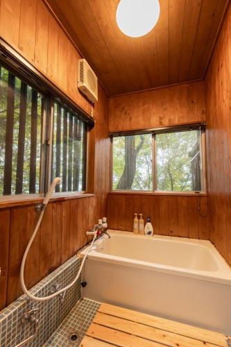 a bath tub in a wooden bathroom with a window at 那須Bitsは1棟貸で愛犬と過ごせる宿でBBQ無料プロジェクター完備 in Nasu