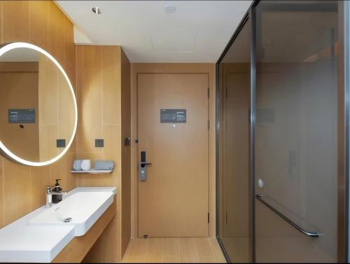 a bathroom with a shower and a sink and a mirror at JI Hotel Hangzhou Alibaba Xixi Park in Hangzhou