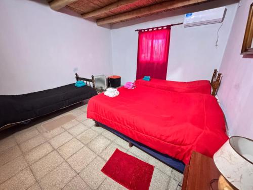 a bedroom with a red bed and a couch at Departamento Guadalupe in Fiambalá