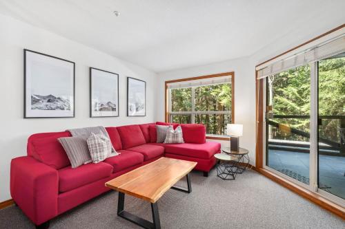 a red couch in a living room with windows at 2BR in The Aspens, Ski In, Ski Out, Pool and Hot Tub, Gas Fireplace, Ski Valet, Gym in Whistler