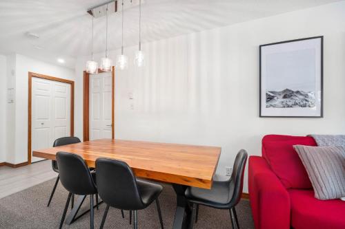 a dining room with a wooden table and a red couch at 2BR in The Aspens, Ski In, Ski Out, Pool and Hot Tub, Gas Fireplace, Ski Valet, Gym in Whistler