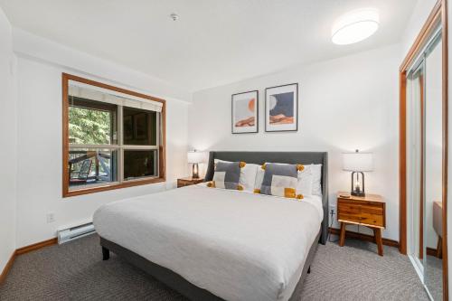 a white bedroom with a bed and a window at 2BR in The Aspens, Ski In, Ski Out, Pool and Hot Tub, Gas Fireplace, Ski Valet, Gym in Whistler