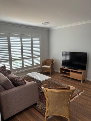 Bundanoon Rochester Guest House في بوندانون: غرفة معيشة مع أريكة وتلفزيون بشاشة مسطحة