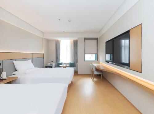 a hotel room with a large bed and a tv at JI Hotel Hangzhou Alibaba Xixi Park in Hangzhou