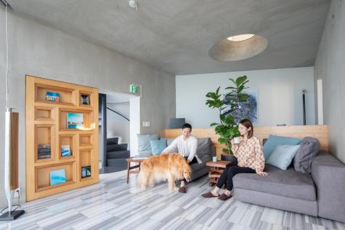 a man and woman sitting in a living room with a dog at 佐島 - Nowhere but Sajima - ペット可 in Yokosuka