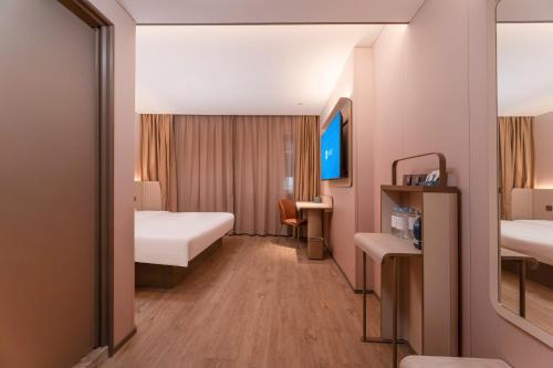 a hotel room with two beds and a tv at Hanting Hotel Nanjing Hexi Wanda in Nanjing