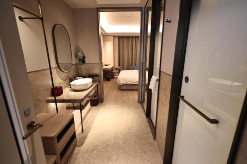 a bathroom with a sink and a room with a bed at Mercure Taiyuan City Centre in Taiyuan