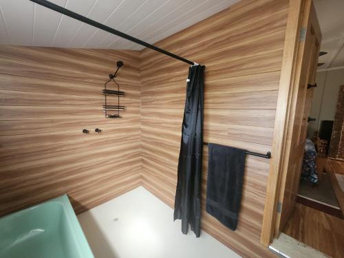 Jack's Shack Kingscote في كنغزكوت: حمام مع حوض استحمام وجدار خشبي