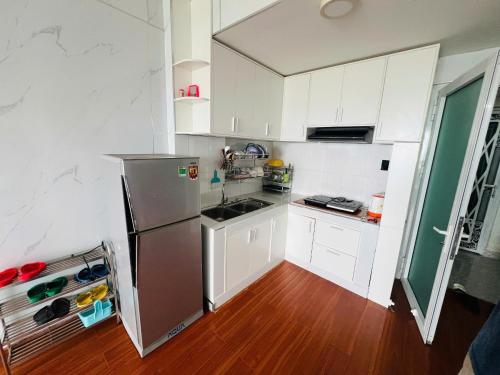 a kitchen with white cabinets and a stainless steel refrigerator at Tom coffee and home stay in Thôn Mỹ Phước