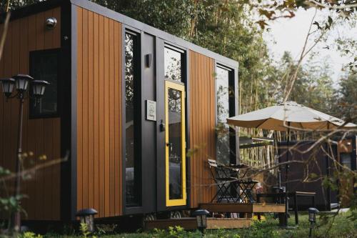 Una pequeña casa naranja y negra con una sombrilla. en Ninekm Forest Wilderness X by Tiny Away, en Wufeng