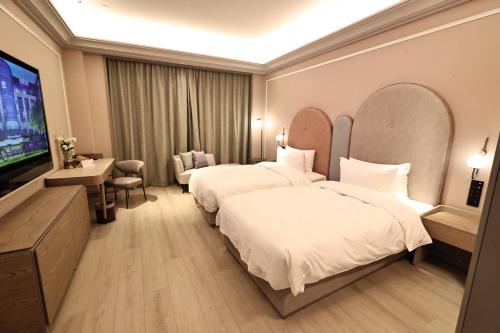 a hotel room with two beds and a flat screen tv at Mercure Taiyuan City Centre in Taiyuan