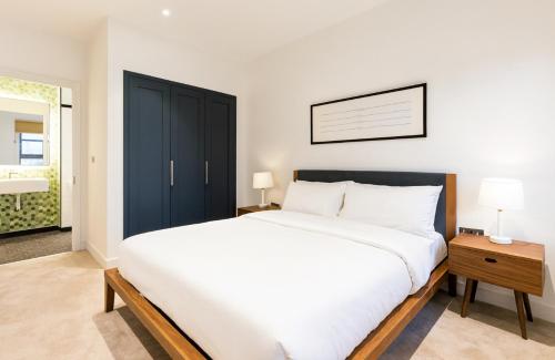 a bedroom with a large white bed with a black cabinet at En-suite Room LUXURIOUS 2 bed Flatshare in London