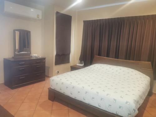 a bedroom with a bed and a dresser and a television at Ben's House Bangsaen in Bangsaen