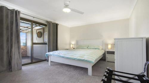 een witte slaapkamer met een bed en een stoel bij Beachway in Orient Point