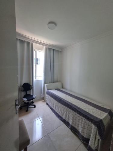 a bedroom with a bed and a chair and a window at Bem vindo ao APTO 403 in Florianópolis