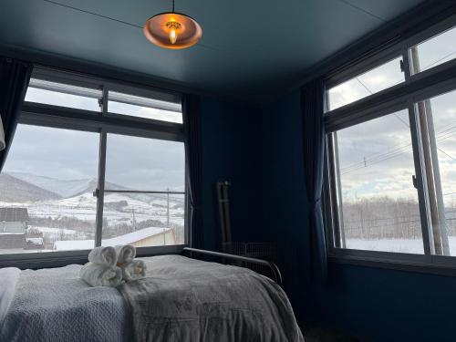 a bedroom with a bed and windows with a view at ルスツリゾート車5分大人数向け貸別荘RusutsuSkiStay111BBQ無料貸し出し花火OK in Rusutsu