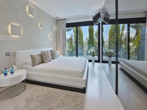 a bedroom with a white bed and a large window at Villa in Ibiza with Infinity Pool and Sea Views in Es Cubells