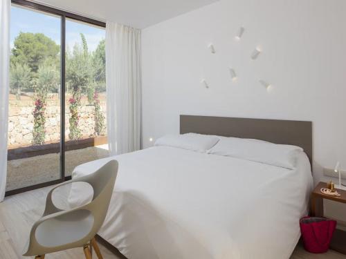 1 dormitorio blanco con 1 cama blanca y 1 silla en Villa in Ibiza with Mountain Views & Pool, en Santa Eulària des Riu