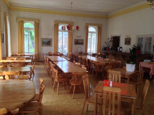 een restaurant met houten tafels, stoelen en ramen bij Hotel Quellenhof in Scuol