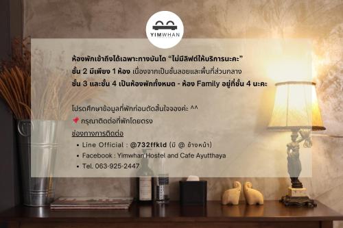 a sign on a wall with a table with a lamp at Yimwhan Hostel & Cafe Ayutthaya in Phra Nakhon Si Ayutthaya