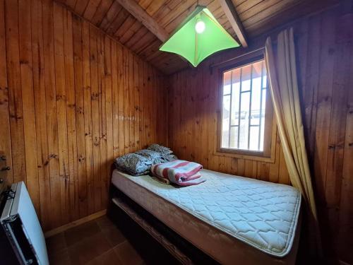 um pequeno quarto com uma cama e uma janela em Cabaña en el Canelillo em Algarrobo