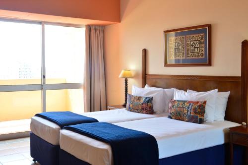 a hotel room with two beds and a window at Pestana Rovuma in Maputo