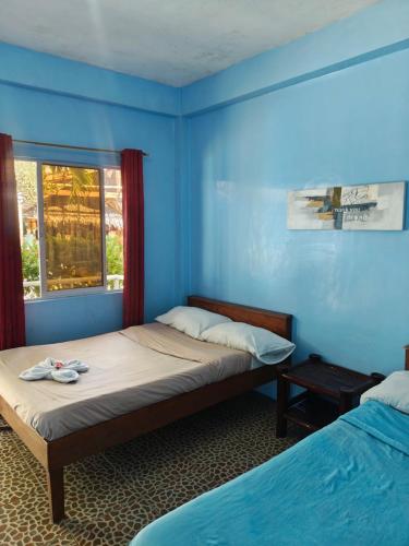a bedroom with two beds and a blue wall at Satosa Beach Resort in San Joaquin