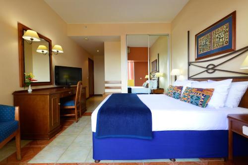 a hotel room with a large bed and a desk at Pestana Rovuma in Maputo