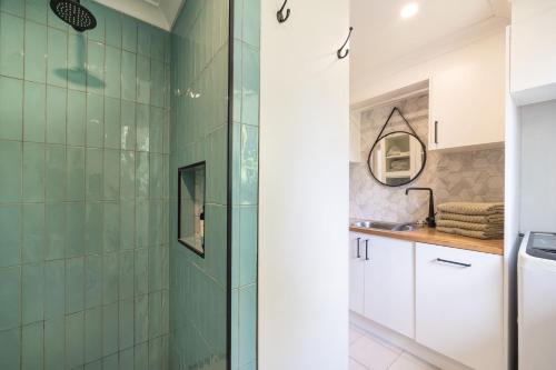 a bathroom with green tiled walls and a shower at Bluegum Beach Stay in Narrawallee