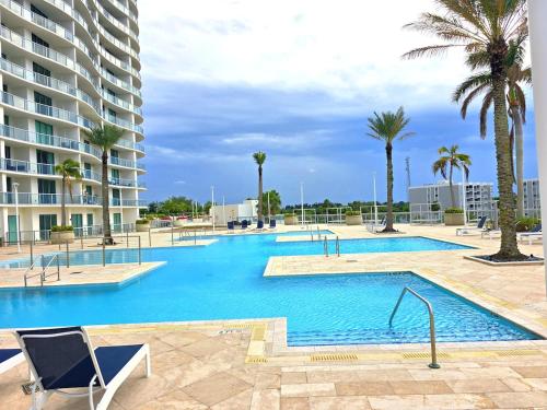 a large swimming pool with palm trees and a building at Lux Vista Retreat, 2BR, 2BA with terrace and pool in Fort Myers
