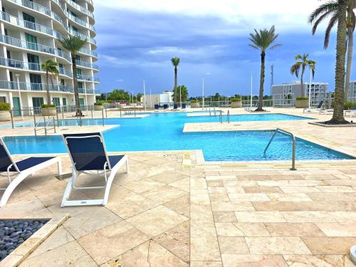 a swimming pool with two chairs and palm trees at Luxury 2BR in Downtown Fort Myers Pool & Terrace in Fort Myers