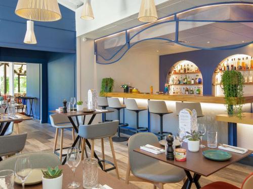 Novotel Aix-en-Provence Pont de L'Arc في آكس أون بروفانس: مطعم بجدران زرقاء وطاولات وكراسي