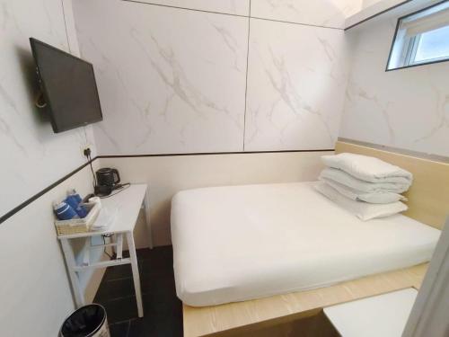 Una pequeña habitación con una cama y un televisor. en Joy Hella Inn, en Hong Kong