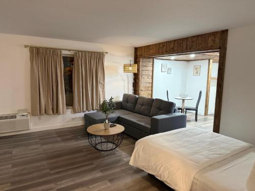 Hôtel Saint-Côme في Saint Come: غرفة نوم بها سرير وأريكة وطاولة