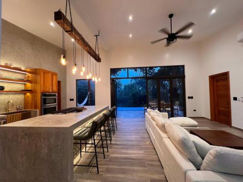 Villa 10 at Chial Reserve Exclusive Jungle Retreat في Big Eddy: مطبخ وغرفة معيشة مع بار مع الكراسي